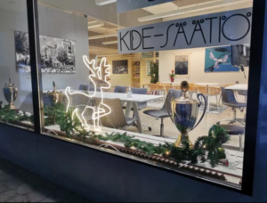 Kide-säätiön ikkuna, jossa valaistu poro ja havuja.